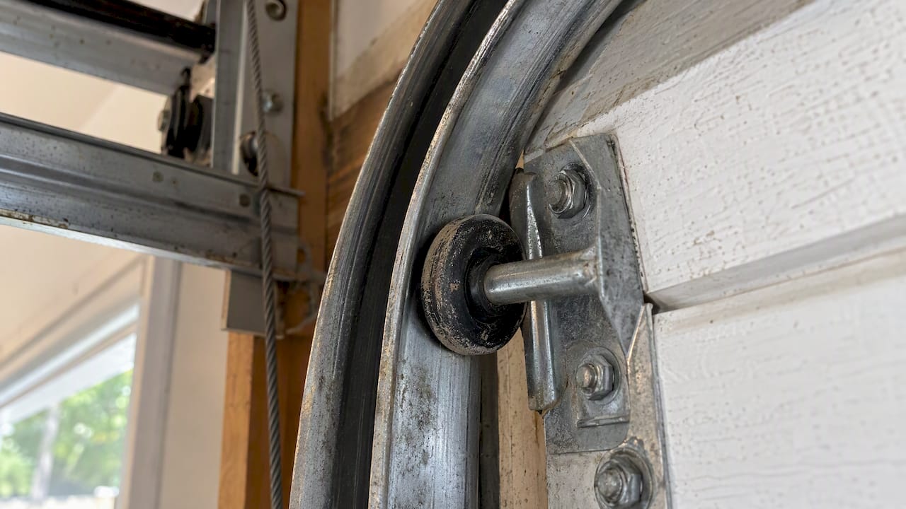 Worn roller seated at a garage door track curve